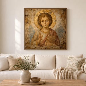 May include: A square wall art print featuring a portrait of a young figure with curly hair, a golden halo, and a red robe, holding a book. The artwork has a textured, aged appearance with muted earth tones and a prominent gold circular background.