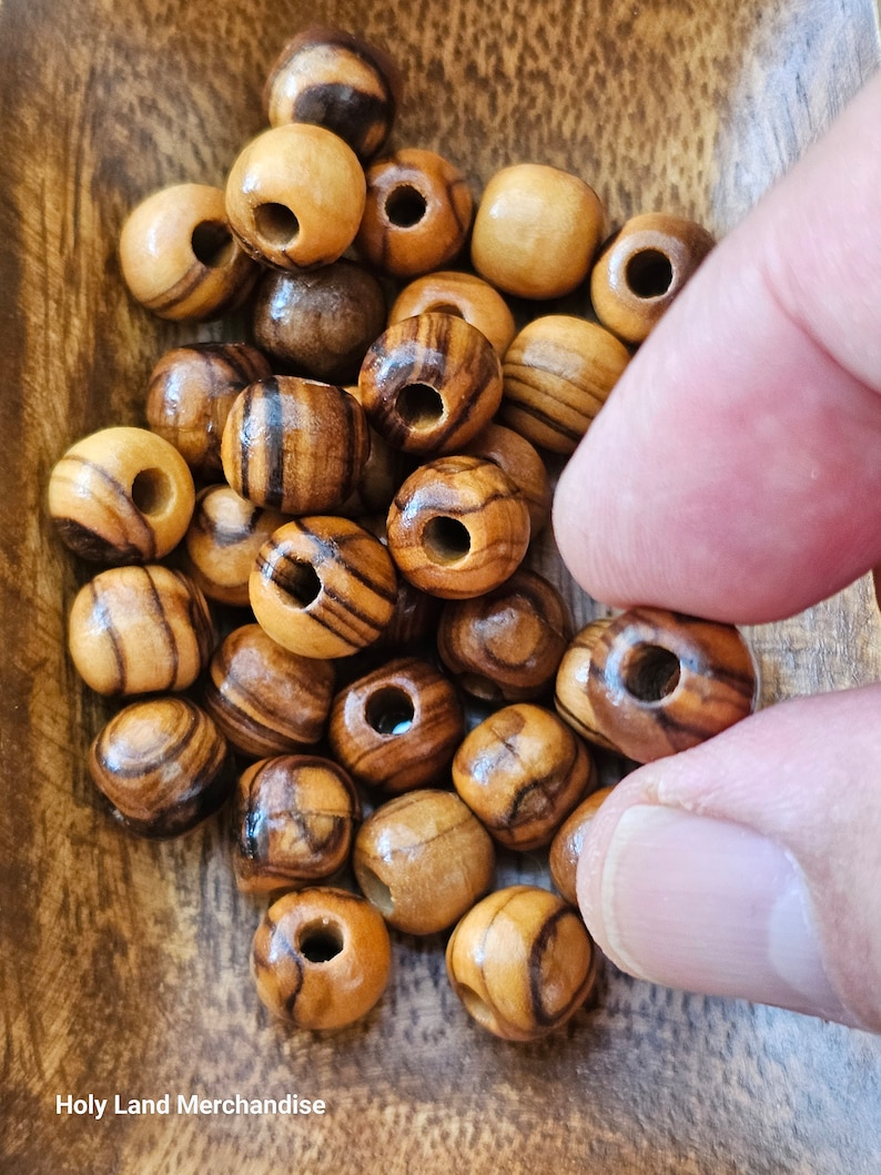 May include: A bowl of brown and tan wooden beads with a hole in the center of each bead. The beads are in a wooden bowl.