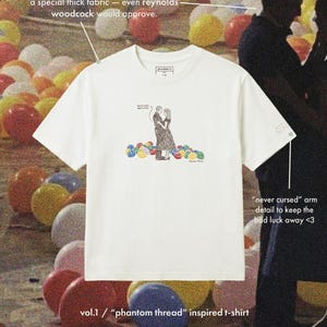 May include: White t-shirt with a graphic of a couple embracing, surrounded by colorful balls. The shirt has text that reads "vol.1 / 'phantom thread' inspired t-shirt" and "greenpink co."