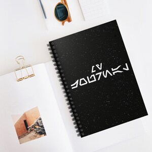 May include: A black spiral notebook with a white star pattern and the text "LV  JOLTMAK" in white.