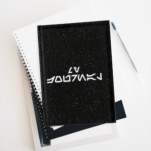 May include: A black notebook with a white star-filled background and the text "LV  YOD7MAK" in white.