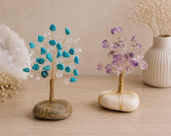 May include: Two decorative wire trees with gemstone leaves. The left tree features turquoise and clear stones on a grey stone base. The right tree features purple amethyst stones on a white stone base. Both trees have gold-coloured wire trunks.