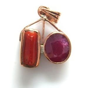 以下が含まれることがあります： 長方形の赤い宝石と丸い濃い赤色の宝石を、銅色の金属フレームにセットしたペンダント。ペンダントにはチェーン用のループが付いています。
