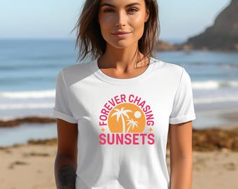 May include: White t-shirt with a pink and orange graphic design. The graphic features a circle with palm trees and a sun inside. The text "FOREVER CHASING SUNSETS" is written around the circle.