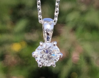 May include: A silver chain necklace with a single round diamond pendant.