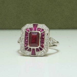 May include: A silver ring with a large, rectangular, dark pink ruby surrounded by smaller rubies and diamonds.