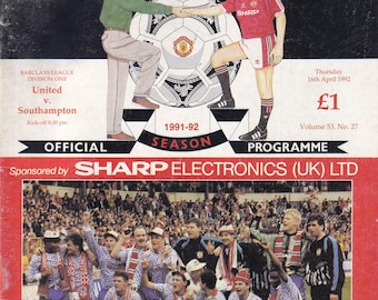 May include: A vintage Manchester United football program cover. The cover features illustrations of two men shaking hands over a soccer ball. The bottom half shows a team celebrating with a trophy.