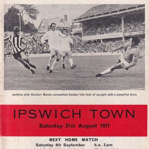 Op de afbeelding: Vintage voetbalprogramma-omslag van Southampton Football Club met een zwart-witfoto van een wedstrijd. De rode banner bovenaan luidt "Southampton Football Club". De onderste banner luidt "Ipswich Town."