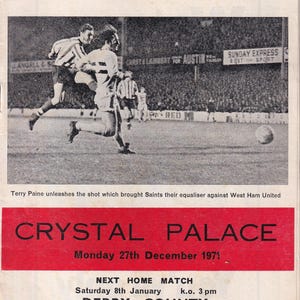 Op de afbeelding: Vintage voetbalprogramma-omslag van Southampton Football Club met een zwart-wit actieopname van een voetbalwedstrijd. De rode banner bovenaan luidt "SOUTHAMPTON FOOTBALL CLUB". De onderste banner is rood met "CRYSTAL PALACE" en wedstrijdgegevens.