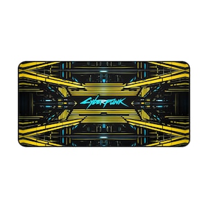 May include: Rectangular desk mat with a geometric design in yellow and black with blue accents. The word "CYBERPUNK" is written in a stylized font across the centre of the mat. The mat has rounded corners.