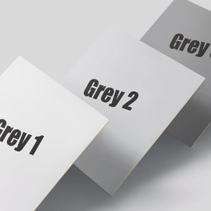 Könnte beinhalten: Drei quadratische Karten, die übereinander gestapelt sind. Die oberste Karte ist dunkelgrau mit dem Text "Grau 3" in Schwarz. Die mittlere Karte ist hellgrau mit dem Text "Grau 2" in Schwarz. Die unterste Karte ist weiß mit dem Text "Grau 1" in Schwarz.