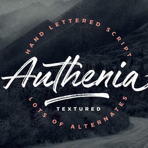 May include: A dark, textured background with a mountain range and a winding road. The word "Authenia" is written in a white, handwritten script font. The text "Hand Lettered Script" and "Lots of Alternates" are in a circular arrangement.