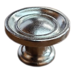 May include: A silver-colored cabinet knob with a rounded top and a circular design. The knob has a short, cylindrical base and a reflective, metallic finish. This hardware is suitable for drawers and cabinets.