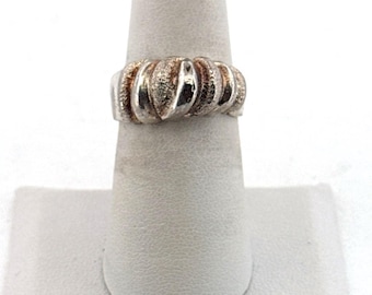 May include: Silver-toned ring with a textured, ribbed design. The ring is displayed on a white ring holder. The ring's surface has a slightly tarnished appearance, adding to its vintage aesthetic. The ring's design is a series of rounded ridges.