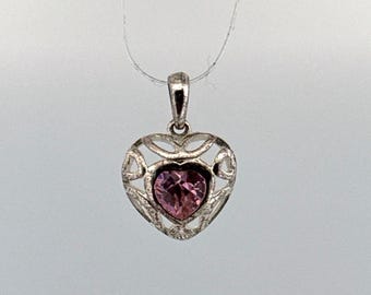 Peut inclure: Pendentif argenté en forme de cœur avec une pierre précieuse rose au centre. Le pendentif présente un motif ajouré autour de la pierre précieuse et est suspendu à une fine chaîne argentée. La pierre est rose clair.