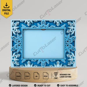 May include: A rectangular picture frame featuring a layered snowflake design in shades of blue. The frame has a central rectangular opening and is displayed on a wooden base. The image includes a yellow digital file icon and text labels for SVG, DXF, AI, and PDF file formats, along with the text "DESIGNED FOR LASER CUTTING."