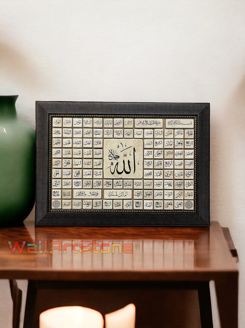 May include: A framed artwork with a black frame and a beige background. The artwork features a grid of Arabic calligraphy with the word "Allah" in the center. The calligraphy is in gold and black.