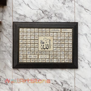 May include: A framed Islamic art print with a black frame and gold accents. The print features a large Arabic word "Allah" in the center surrounded by smaller Arabic words in a grid pattern.