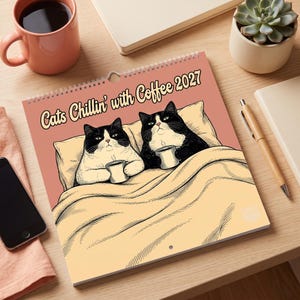 May include: A 2027 wall calendar featuring a graphic illustration of two black and white cats lying in bed under a yellow blanket, each holding a coffee mug. The text at the top reads Cats Chillin' with Coffee 2027 in a dark brown font.