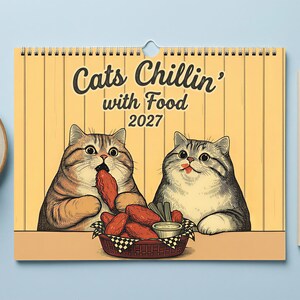 Puede incluir: Un calendario de pared con fondo amarillo que muestra el texto "Cats Chillin' with Food 2027" y una ilustraci&oacute;n de dos gatos comiendo alitas de pollo de una cesta. El calendario est&aacute; encuadernado en espiral con un orificio central.