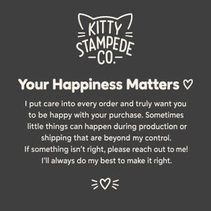 May include: A dark gray informational card featuring the white text logo Kitty Stampede Co. with cat ears above it. The card reads: Your Happiness Matters, followed by a message about customer care, production, shipping, and contact instructions.