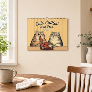 Puede incluir: Un calendario de pared 2027 con fondo amarillo de l&iacute;neas verticales y una ilustraci&oacute;n de dos gatos comiendo pollo frito de una cesta. El texto dice Cats Chillin' with Food 2027 en una fuente marr&oacute;n oscuro manuscrita y sin remates.