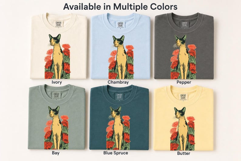 Pu&ograve; includere: Sei magliette nei colori avorio, chambray, pepe, baia, abete blu e burro. Ogni maglietta presenta una grafica di un gatto in piedi tra fiori rossi. Il testo "Available in Multiple Colors" appare in alto, con i nomi dei colori sotto.
