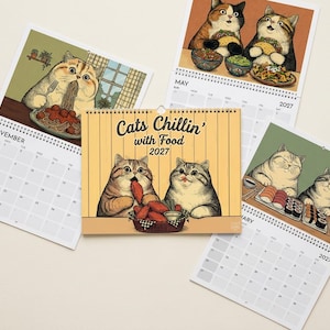 Puede incluir: Un calendario de pared 2027 titulado Cats Chillin' with Food con ilustraciones de gatos comiendo diversas comidas. La portada muestra dos gatos con pollo frito, mientras que las p&aacute;ginas interiores muestran gatos disfrutando de espaguetis, tacos y sushi.