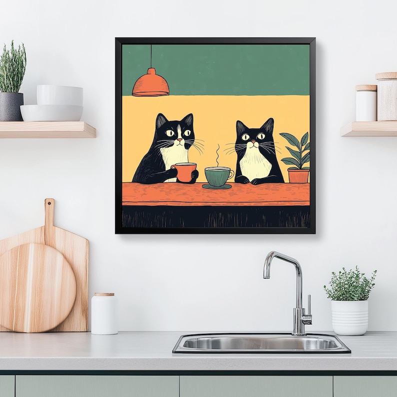 K&ouml;nnte beinhalten: Ein gerahmter Kunstdruck mit zwei schwarz-wei&szlig;en Katzen an einem Tisch, jede mit einer Tasse Kaffee. Der Hintergrund ist gelb und gr&uuml;n, mit einer kleinen Pflanze und einer orangefarbenen Pendelleuchte. Die Katzen scheinen sich zu entspannen.