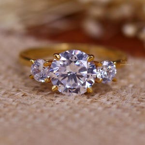 Beloftering met drie stenen in glanzend goud / met briljant geslepen stenen / Een betekenisvolle verlovingsring voor je liefdesverhaal.