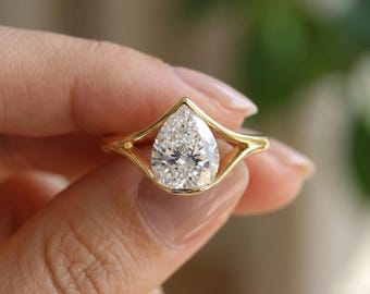 Anello di fidanzamento con moissanite taglio a pera, fede nuziale in oro 14 carati con gambo diviso e incastonatura a castone.
