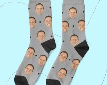 May include: A pair of gray socks with a black polka dot pattern. Each polka dot is a person's face.