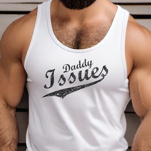 Könnte beinhalten: Weißes Tanktop mit dem Text "Daddy Issues" in verblichener schwarzer Schrift. Das Tanktop ist ärmellos und hat einen Rundhalsausschnitt. Die Person auf dem Bild trägt eine Sonnenbrille und einen Vollbart.