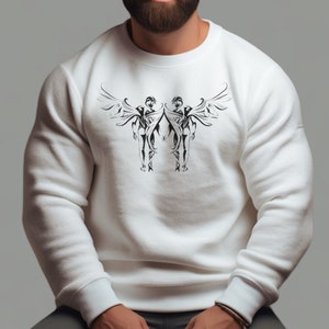 Pode incluir: Camisola branca com uma estampa gráfica em preto e branco de dois anjos com asas. O gráfico está centralizado no peito da camisola.