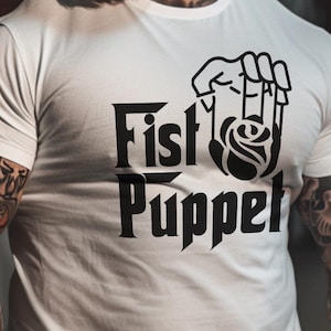 May include: A white t-shirt with a black graphic of a fist holding a rose and the text "Fist Puppet".