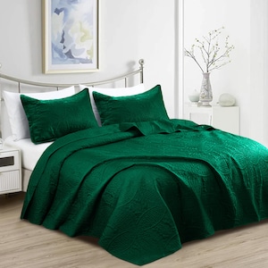Puede incluir: Una cama est&aacute; hecha con una colcha acolchada verde oscuro y dos fundas de almohada a juego. La ropa de cama tiene un estampado de cachemira texturizado. La cama est&aacute; hecha con s&aacute;banas blancas y est&aacute; contra una pared blanca con una imagen enmarcada.