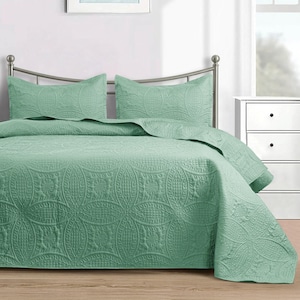 Puede incluir: Un juego de colcha verde menta con dos fundas de almohada a juego. La ropa de cama presenta un patr&oacute;n floral y geom&eacute;trico en relieve detallado. La cama est&aacute; hecha con la colcha y las fundas de almohada, lista para usar.