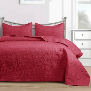 Puede incluir: Un edred&oacute;n acolchado rojo y dos fundas de almohada con un intrincado patr&oacute;n circular. La ropa de cama se muestra en una estructura de cama de metal en un dormitorio. El color es un rojo intenso y rico.
