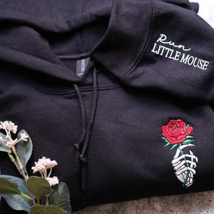 a black sweatshirt with a rose embroidered on it
