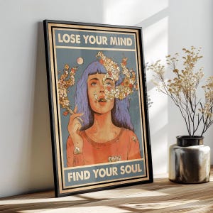 May include: Framed art print featuring a woman with blue hair and floral elements, holding a cigarette. The artwork includes the text "LOSE YOUR MIND" and "FIND YOUR SOUL" in a vintage style, framed in black.