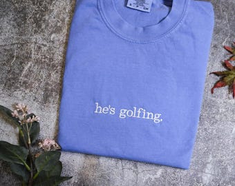 Comfort Colors® He's Golfing Shirt, Golfing Season Shirt, Golfer Wife Shirt, Golfing Mom Shirt, Golf Player Shirt for Mom, Golf Lover Shirt