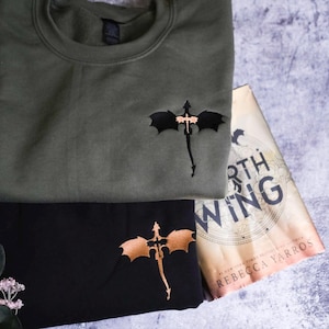 a green shirt with a bat on it next to a book
