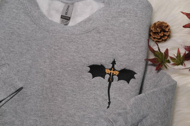 a gray sweater with a bat embroidered on it