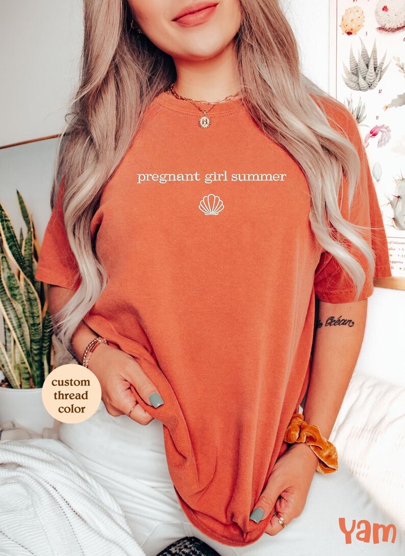 a woman wearing an orange shirt with the words pregnant girl summer on it