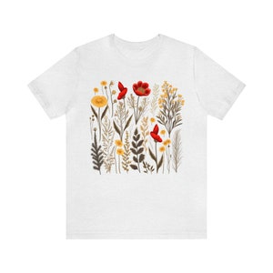 May include: White t-shirt with a floral print featuring red and yellow flowers and green stems.