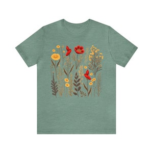 May include: A teal blue t-shirt with a floral print featuring red poppies and yellow wildflowers.