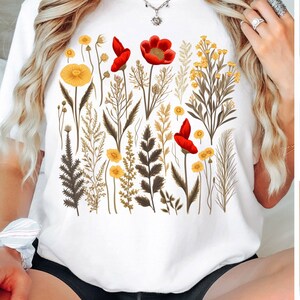 May include: White t-shirt with a floral print featuring red and yellow flowers and green leaves.