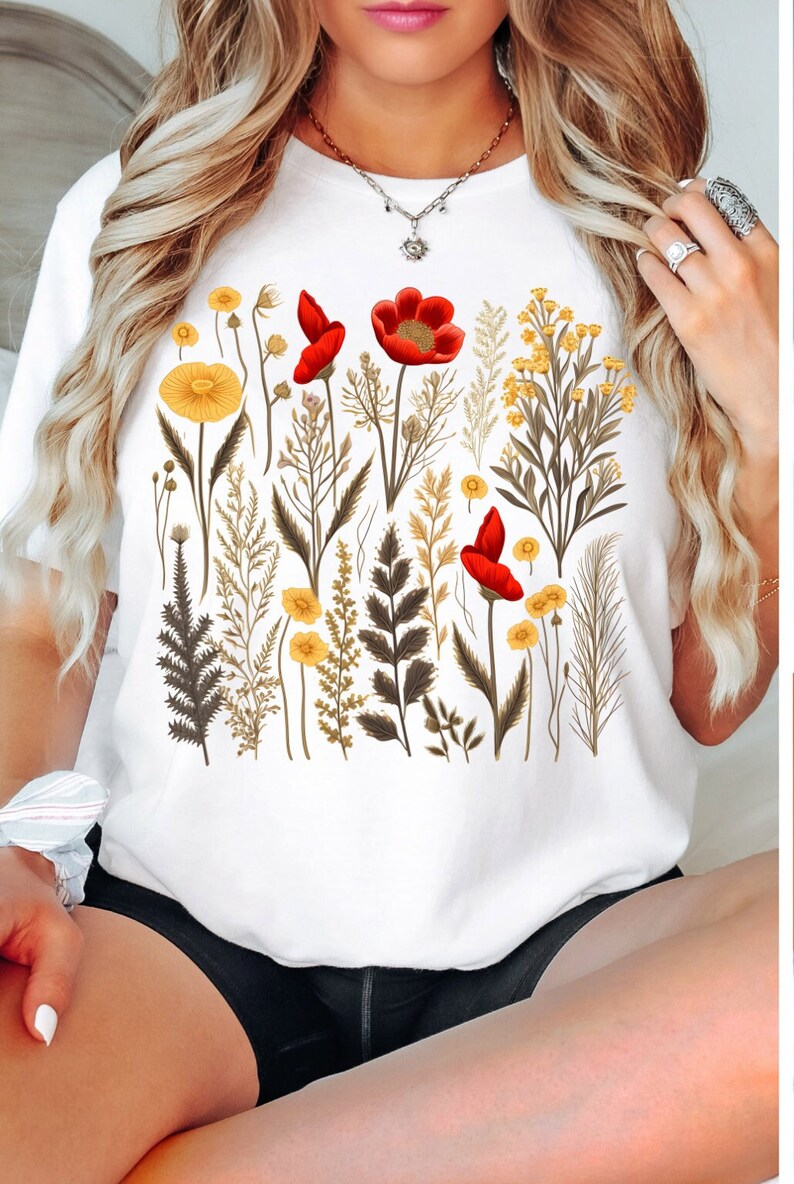 May include: White t-shirt with a floral print featuring red and yellow flowers and green leaves.
