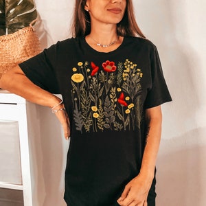 May include: Black t-shirt with a floral print featuring red and yellow flowers. The print is a botanical illustration of various flowers and leaves.