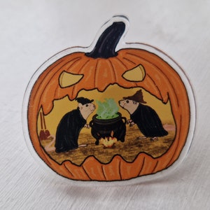 May include: A carved orange pumpkin with a scary face. Inside the pumpkin, two mice wearing hats are stirring a cauldron of green liquid.